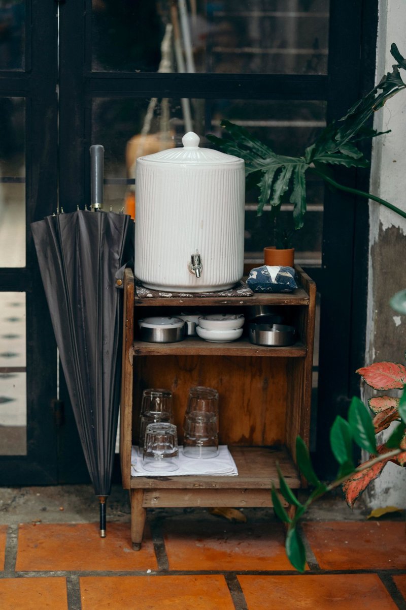 A countertop water dispenser on a wooden stand in a home kitchen corner beside a window